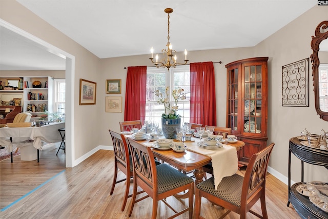 dining room with light wood-style floors, a notable chandelier, and baseboards