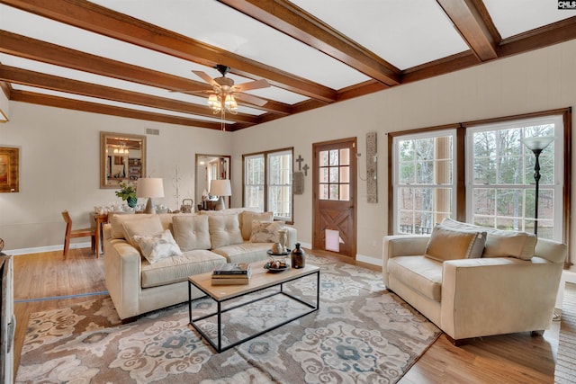 living room featuring a ceiling fan, light wood-type flooring, beam ceiling, and baseboards