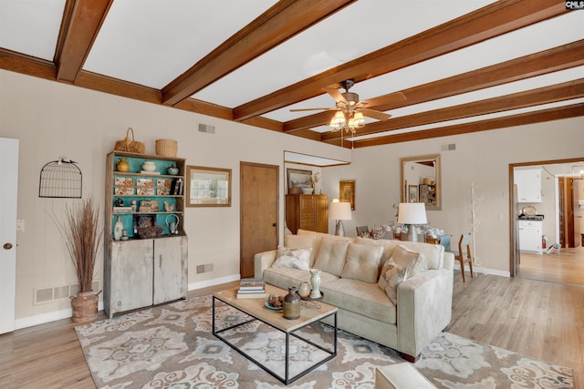 living room featuring light wood finished floors, beam ceiling, and visible vents