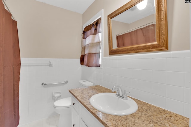 bathroom with wainscoting, tile walls, toilet, and vanity