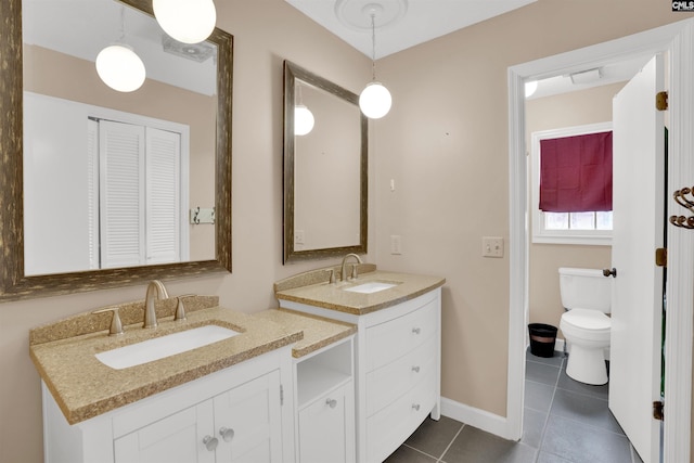 bathroom featuring toilet, two vanities, a sink, and tile patterned flooring