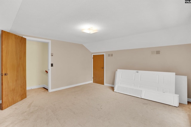 interior space featuring lofted ceiling, carpet flooring, visible vents, and baseboards