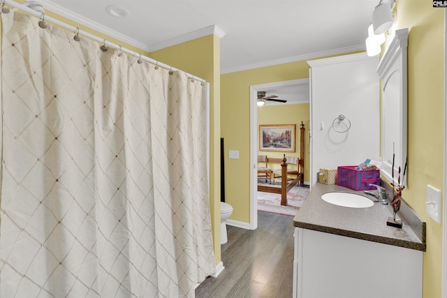 full bathroom featuring a ceiling fan, toilet, wood finished floors, crown molding, and vanity