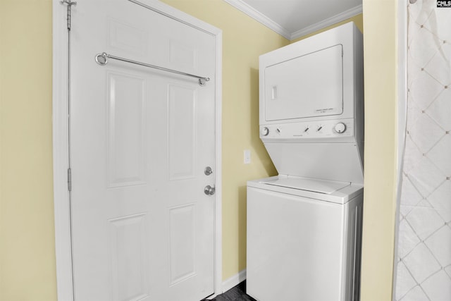 clothes washing area with baseboards, stacked washer and dryer, laundry area, and crown molding