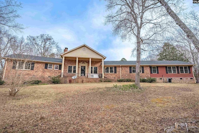 view of front of home featuring a chimney, crawl space, cooling unit, a porch, and brick siding