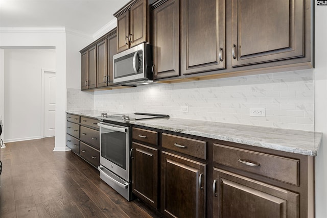 kitchen featuring dark brown cabinetry, tasteful backsplash, appliances with stainless steel finishes, dark wood-type flooring, and crown molding