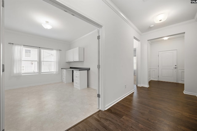 interior space featuring ornamental molding, dark wood-type flooring, dark countertops, and white cabinetry