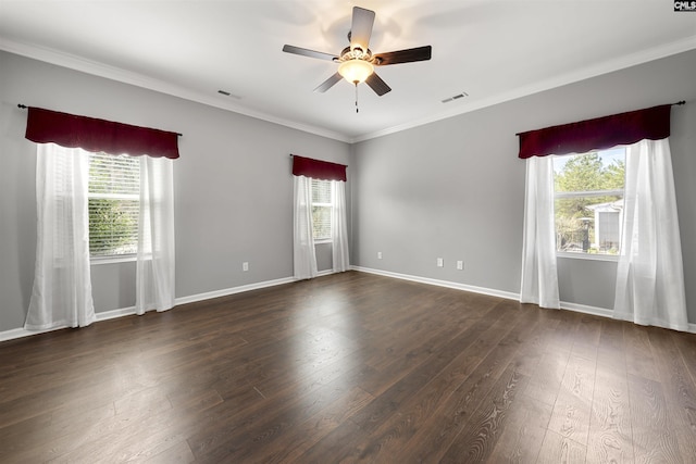 spare room featuring a healthy amount of sunlight, crown molding, visible vents, and dark wood-type flooring