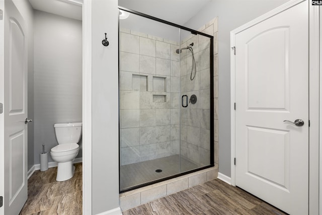 full bath with a stall shower, wood finished floors, toilet, and baseboards