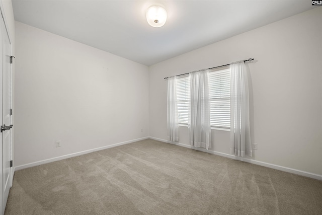 unfurnished room with light carpet and baseboards