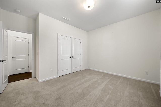 unfurnished bedroom with a closet, carpet flooring, visible vents, and baseboards