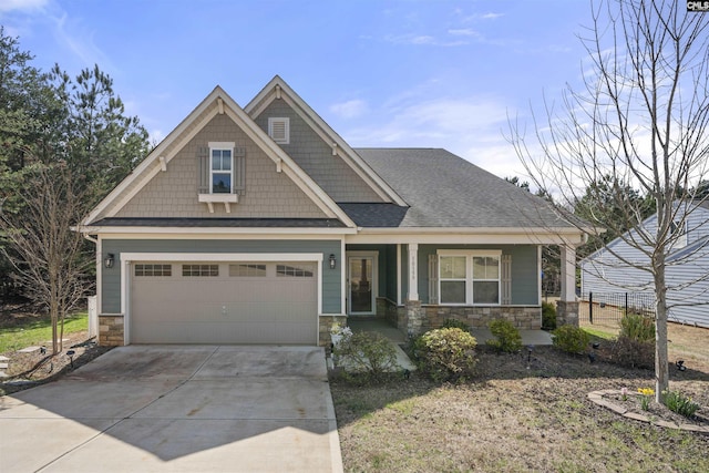 craftsman-style home featuring covered porch, stone siding, a shingled roof, and driveway