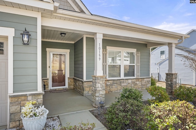 view of exterior entry with a porch and stone siding