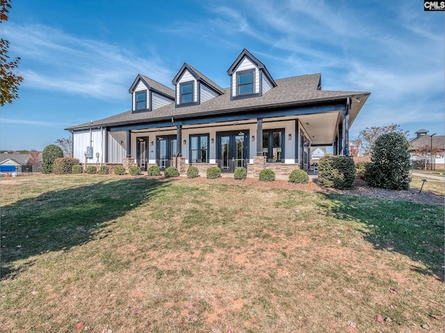 view of front of home featuring covered porch, a shingled roof, and a front lawn