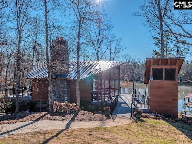 view of property exterior with stone siding, metal roof, and a chimney