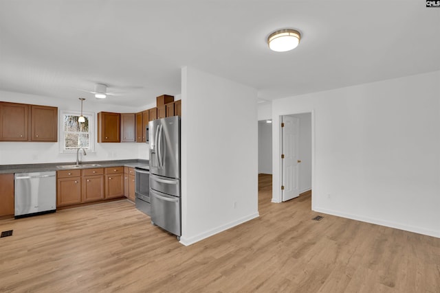 kitchen featuring appliances with stainless steel finishes, light wood-type flooring, a sink, and visible vents