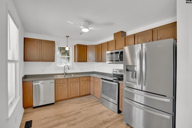 kitchen with visible vents, dark countertops, light wood-style flooring, stainless steel appliances, and a sink