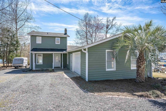 view of front of home featuring covered porch, driveway, and a chimney