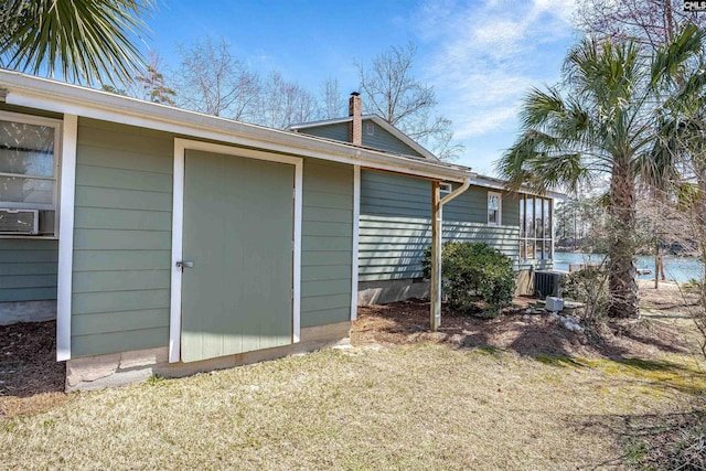 view of property exterior with a chimney, central AC unit, cooling unit, and an outdoor structure