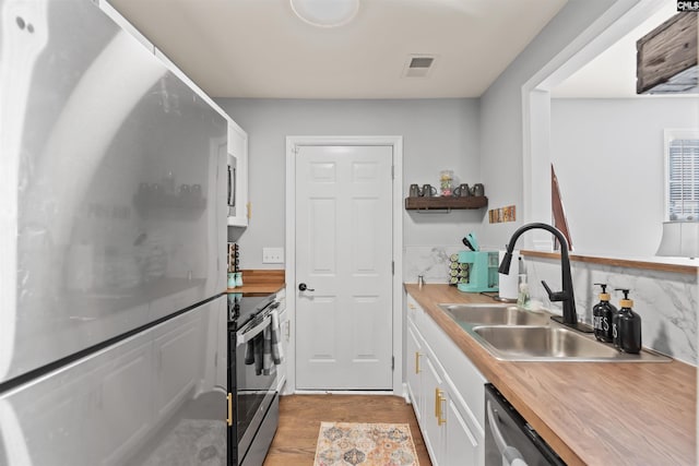 kitchen featuring stainless steel appliances, butcher block countertops, visible vents, white cabinetry, and open shelves