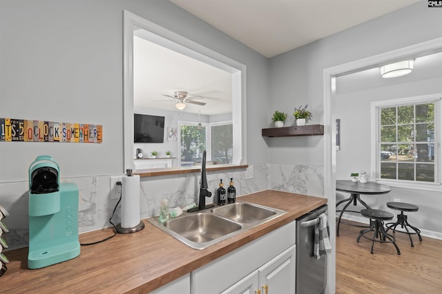 kitchen with dishwasher, plenty of natural light, white cabinetry, and a sink