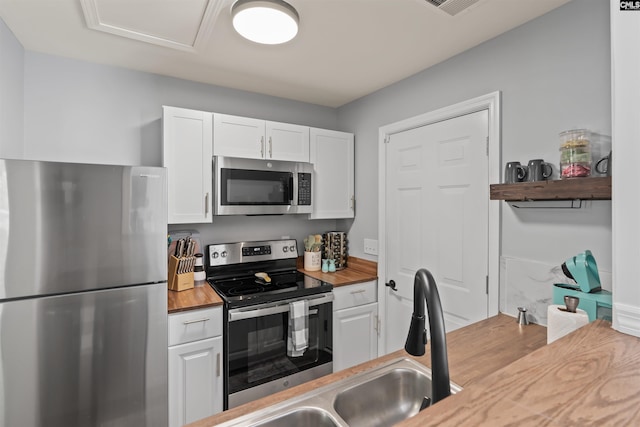 kitchen featuring stainless steel appliances, white cabinetry, wood counters, and open shelves