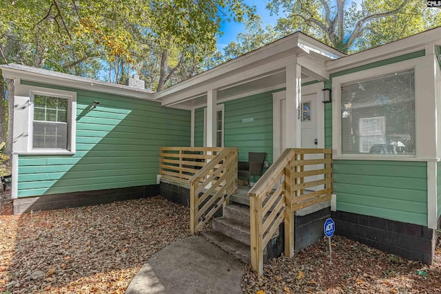 property entrance featuring a chimney and a porch