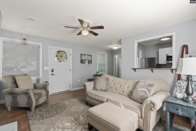 living area with a ceiling fan, baseboards, visible vents, and wood finished floors