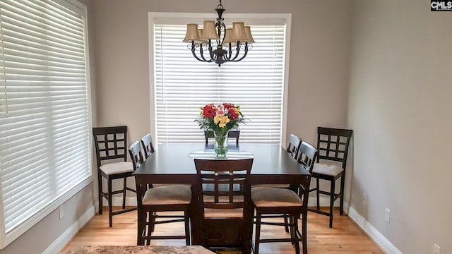 dining room with a chandelier, light wood-type flooring, and baseboards