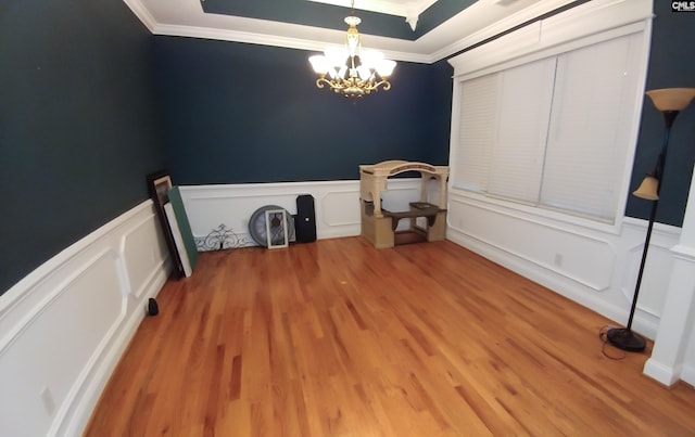 clothes washing area with crown molding, a decorative wall, wood finished floors, and an inviting chandelier