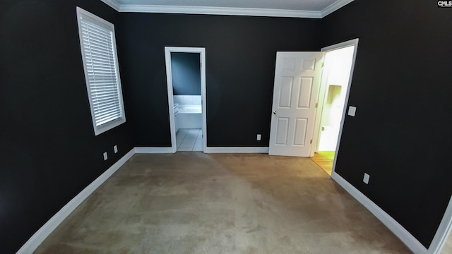 unfurnished bedroom with light carpet, ensuite bath, baseboards, and crown molding