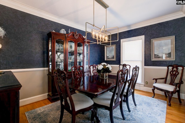 dining space with baseboards, wainscoting, ornamental molding, wood finished floors, and a notable chandelier