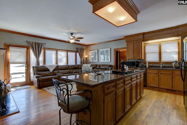 kitchen with black appliances, plenty of natural light, a kitchen bar, and a kitchen island