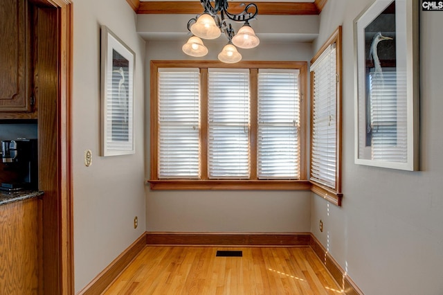 unfurnished dining area with light wood-type flooring, baseboards, visible vents, and a chandelier