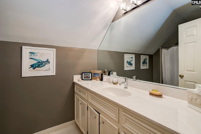 bathroom featuring lofted ceiling, tile patterned floors, baseboards, and vanity