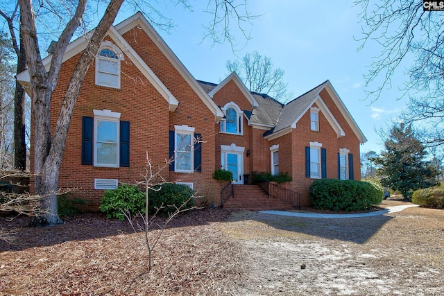 traditional-style home featuring brick siding and roof with shingles