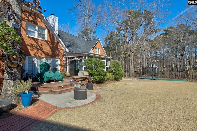 view of yard featuring a trampoline, a patio, and a wooden deck