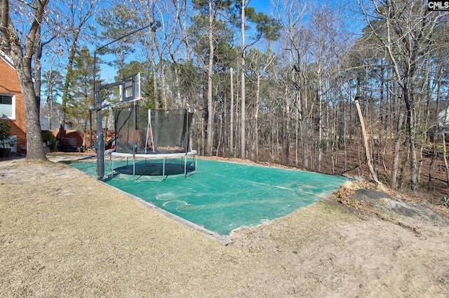 view of basketball court with a trampoline and a yard