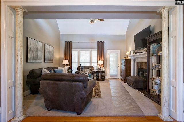 living area featuring ceiling fan, decorative columns, a fireplace, and vaulted ceiling