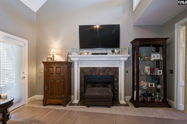 living room featuring carpet floors, vaulted ceiling, baseboards, and a premium fireplace