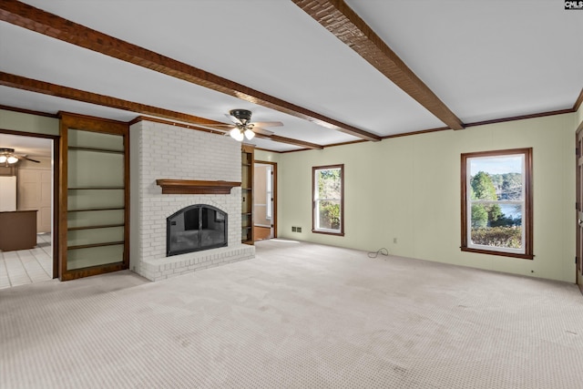 unfurnished living room featuring light carpet, a fireplace, a ceiling fan, and beamed ceiling