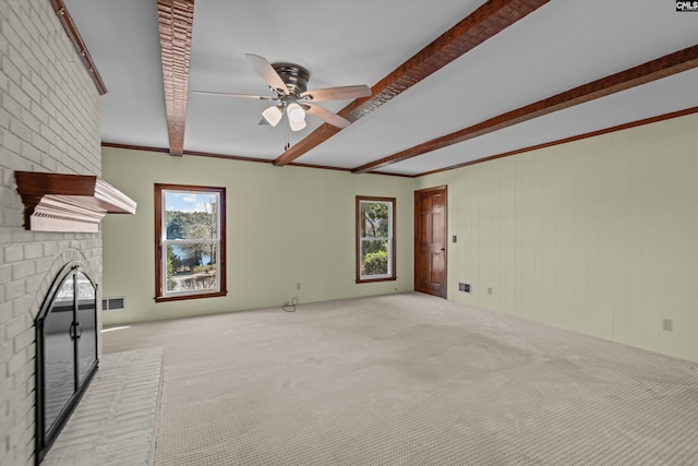 unfurnished living room featuring a brick fireplace, carpet, ceiling fan, and beamed ceiling