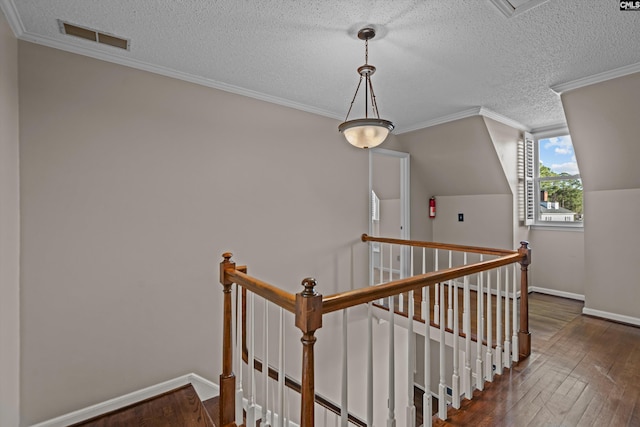 stairs with a textured ceiling, visible vents, baseboards, ornamental molding, and wood-type flooring