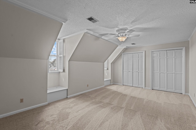 additional living space with a textured ceiling, ceiling fan, visible vents, baseboards, and carpet