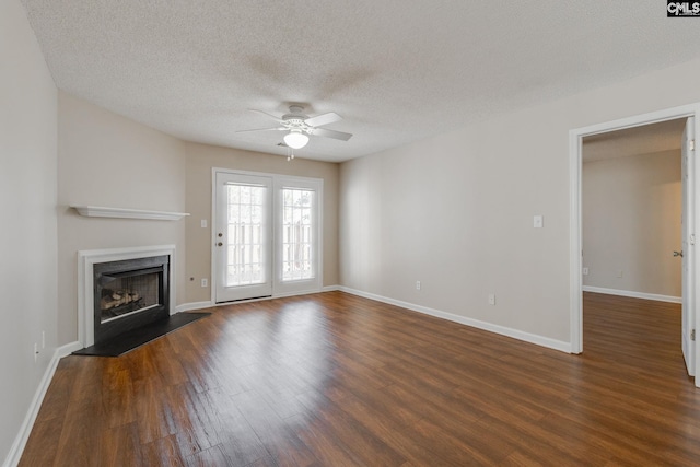 unfurnished living room with ceiling fan, a fireplace, dark wood finished floors, and a textured ceiling