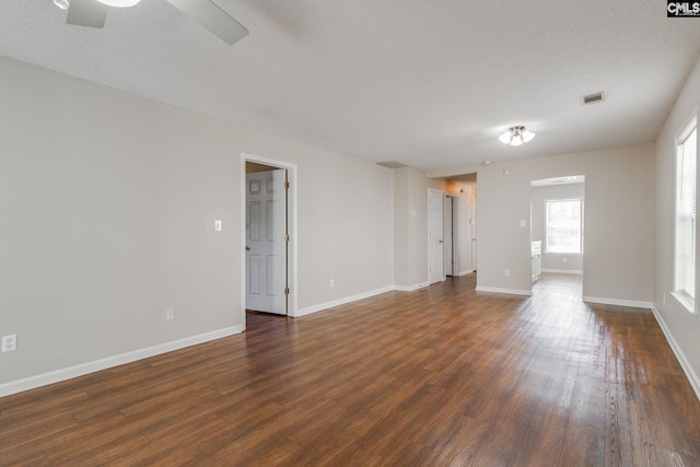 spare room with a textured ceiling, dark wood-type flooring, visible vents, and baseboards