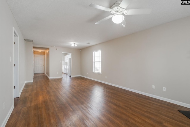 spare room featuring dark wood-style floors, ceiling fan, and baseboards