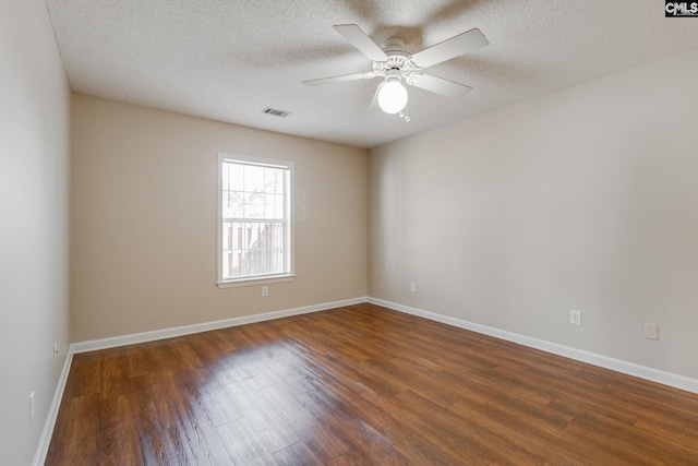 spare room with baseboards, visible vents, ceiling fan, wood finished floors, and a textured ceiling