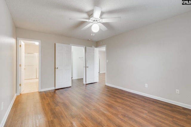 unfurnished bedroom featuring a spacious closet, baseboards, and wood finished floors