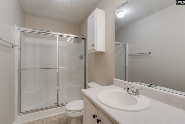 full bathroom featuring vanity, a shower stall, toilet, and a textured ceiling